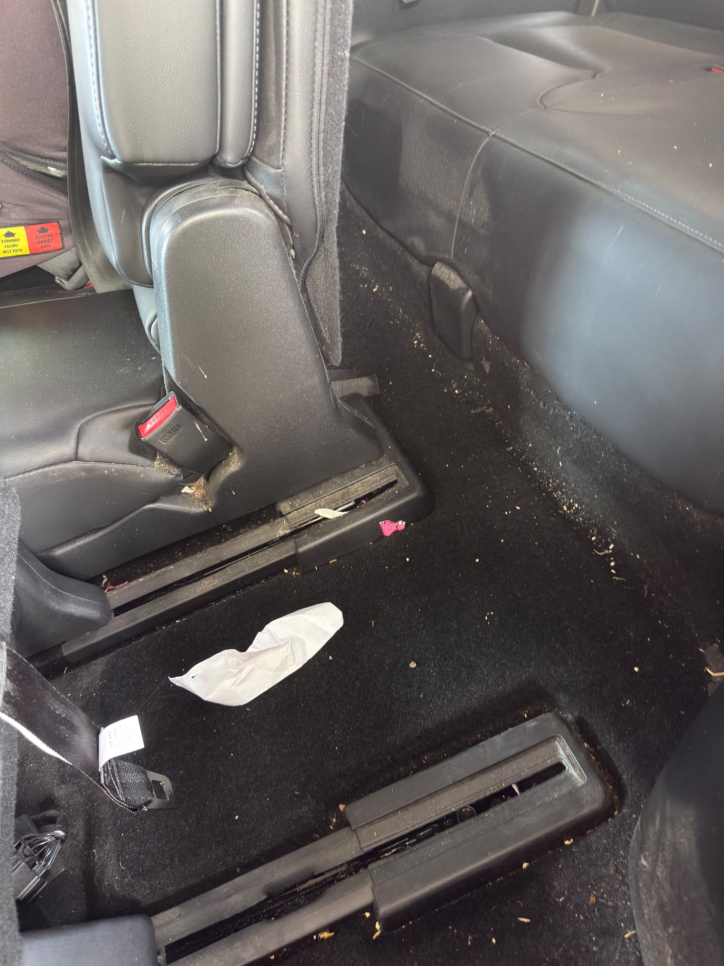 Dirty rear floor carpet covered in crumbs and debris before detailing